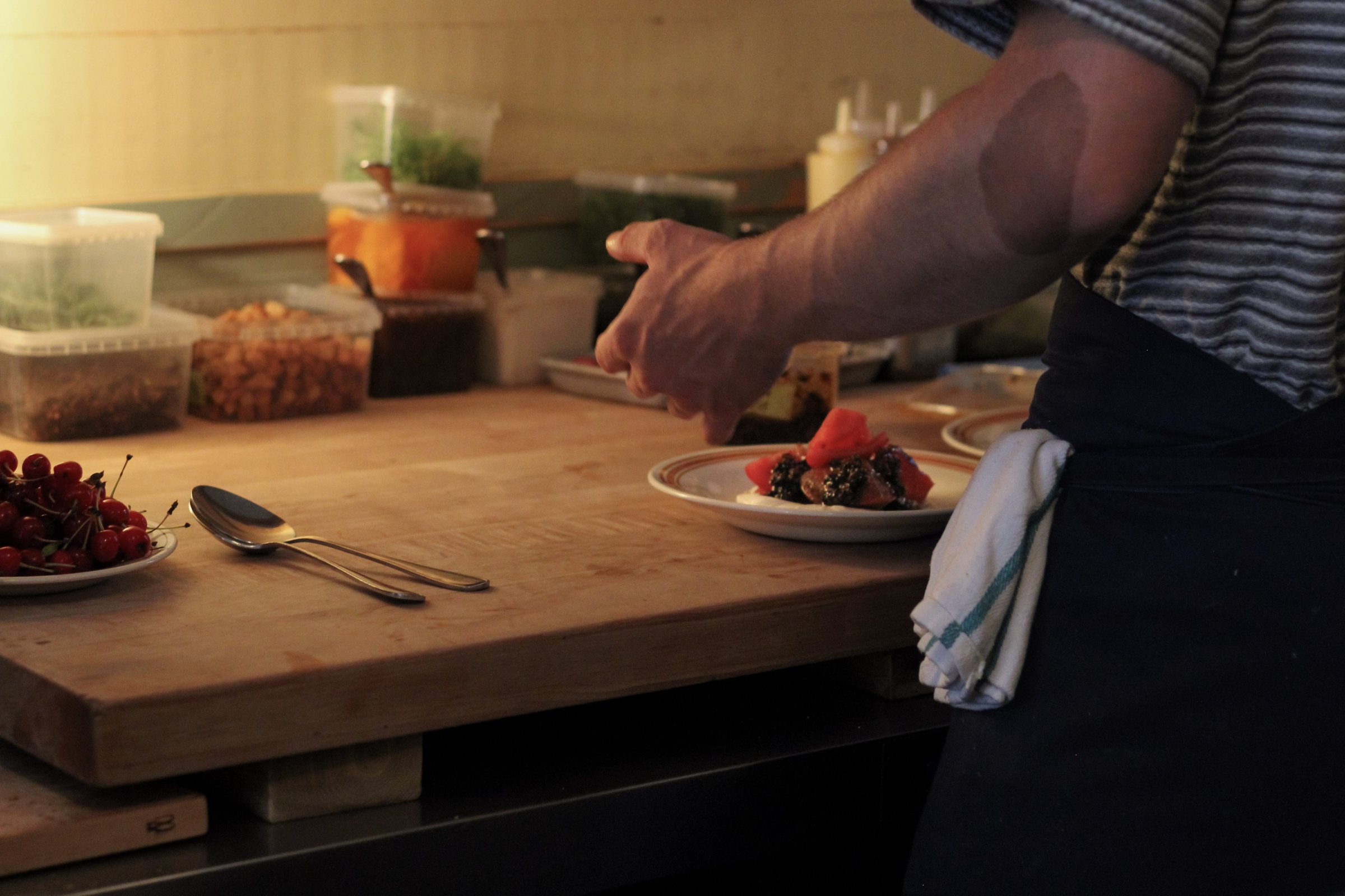 A hand reaching toward a finished plate on the pass