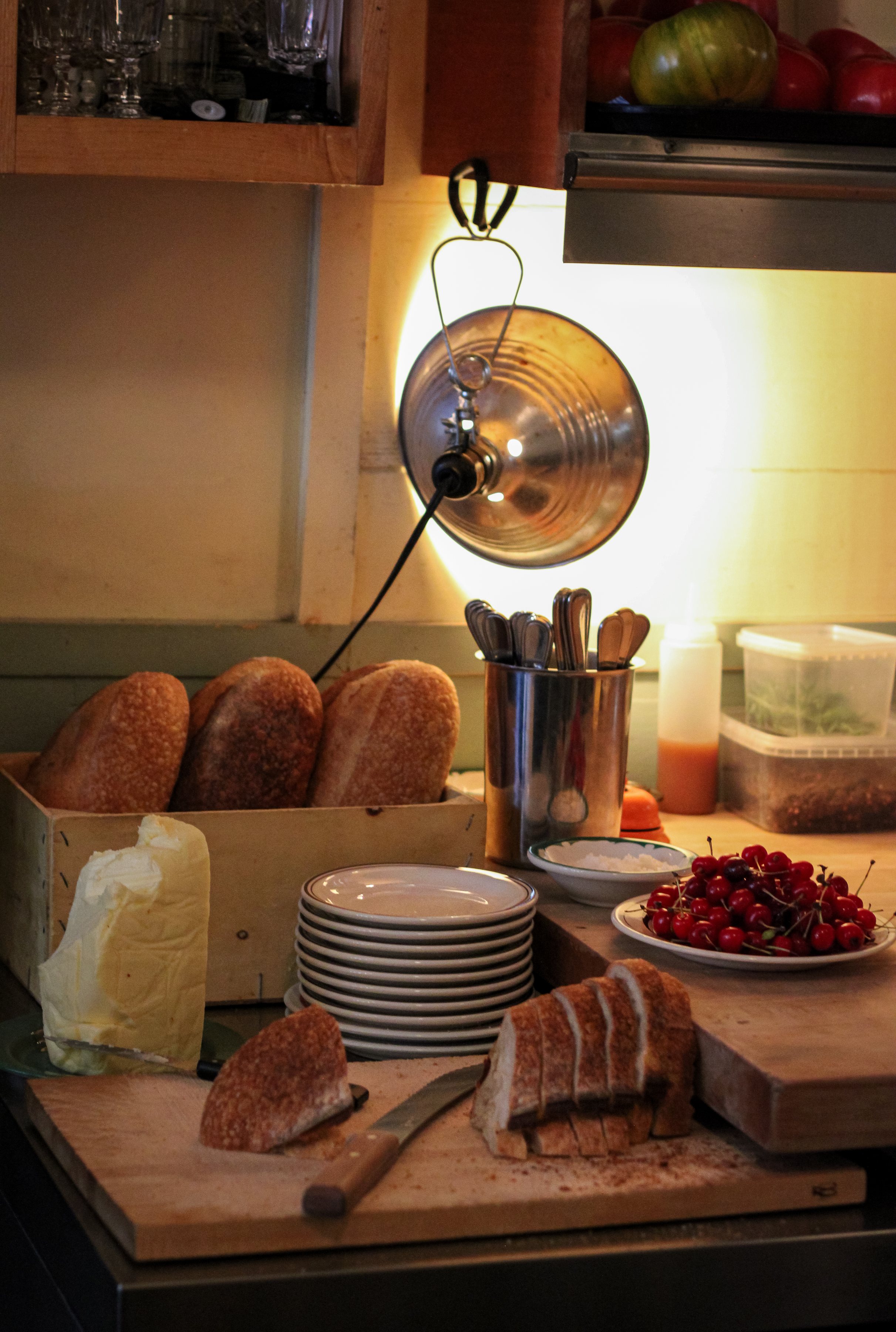 The same Montréal kitchen corner, bread and cherries, at the close of service